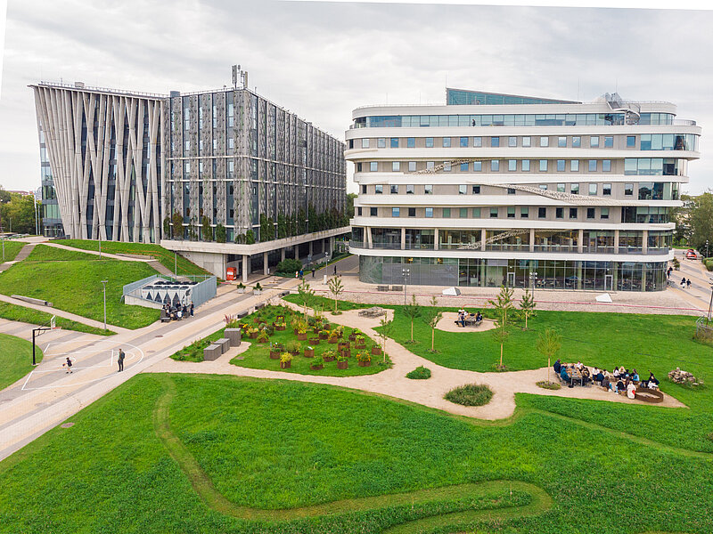 LU Akadēmiskais centrs. Zaļa zāle. Jaunieši sēž pie galda