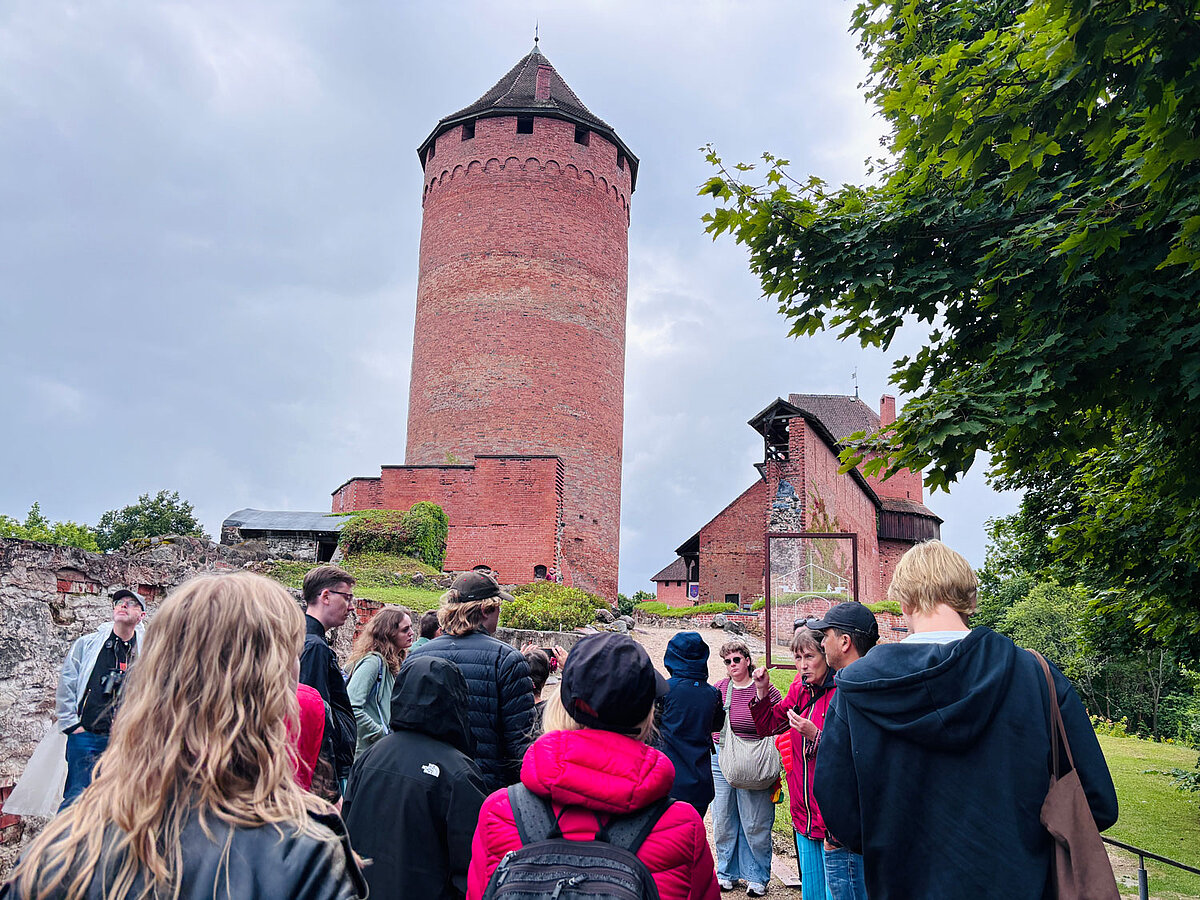 Latviešu valodas un kultūras vasaras skolas dalībnieki ekskursijā pie Turaidas pils torņa.