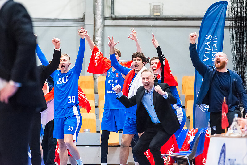 Basketbola komandas rezervisti un personāls priecājas par gūtajiem punktiem