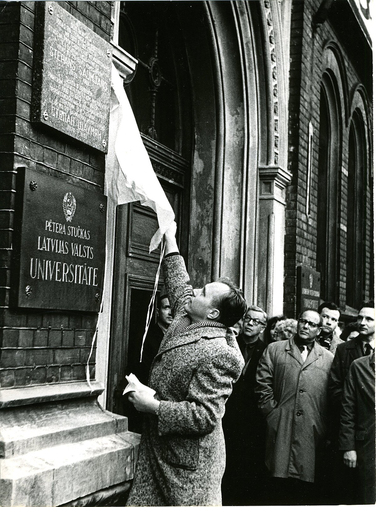 S. Šaumjanam veltītās piemiņas plāksnes atklāšana pie LVU ēkas Raiņa bulvārī 19 1967. gadā – zem piemiņas plāksnes lasāms Pētera Stučkas Latvijas Valsts Universitātes nosaukums (Foto no LU Muzeja krājuma) S. Šaumjanam veltītās piemiņas plāksnes atklāšana pie LVU ēkas Raiņa bulvārī 19 1967. gadā – zem piemiņas plāksnes lasāms Pētera Stučkas Latvijas Valsts Universitātes nosaukums (Foto no LU Muzeja krājuma)