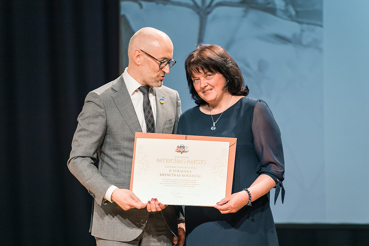 Minister of Health Daniels Pavļuts presents a certificate of recognition to Iveta Strode, Director of P. Stradiņš Medical College of the University of Latvia