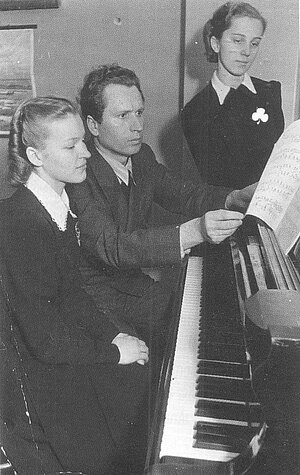 Ella Detlova (stāv) ar klavieru skolotāju Arvīdu Žilinski, 1939. gads. No A. Mellupes grāmatas “Atvērtās durvis: Rīgas pirmā ģimnāzija portretos un notikumos”.