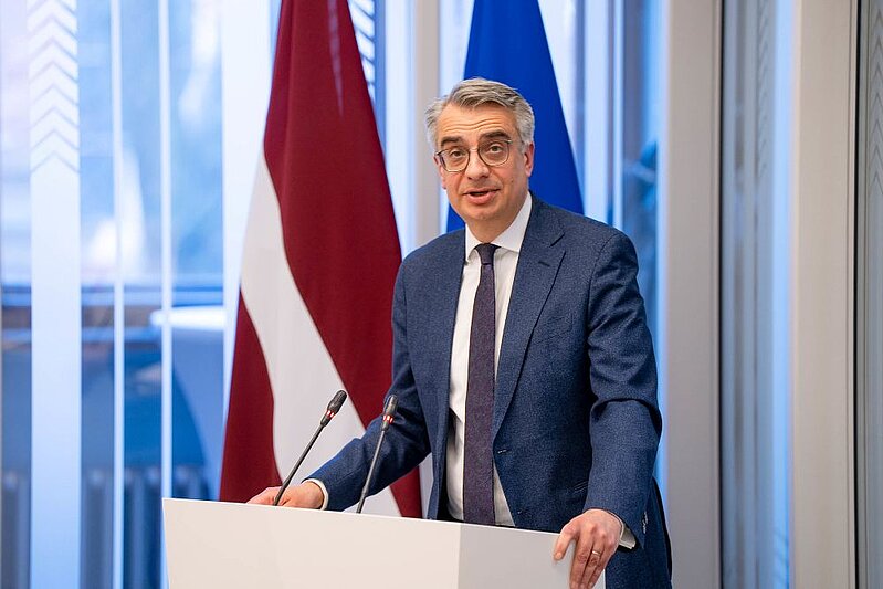 LU profesors Daunis Auers uzstājas Saeimā. Fonā Latvijas un ES karogi. 