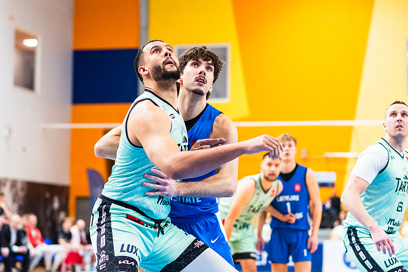 Basketbolisti spēles momentā zem groza