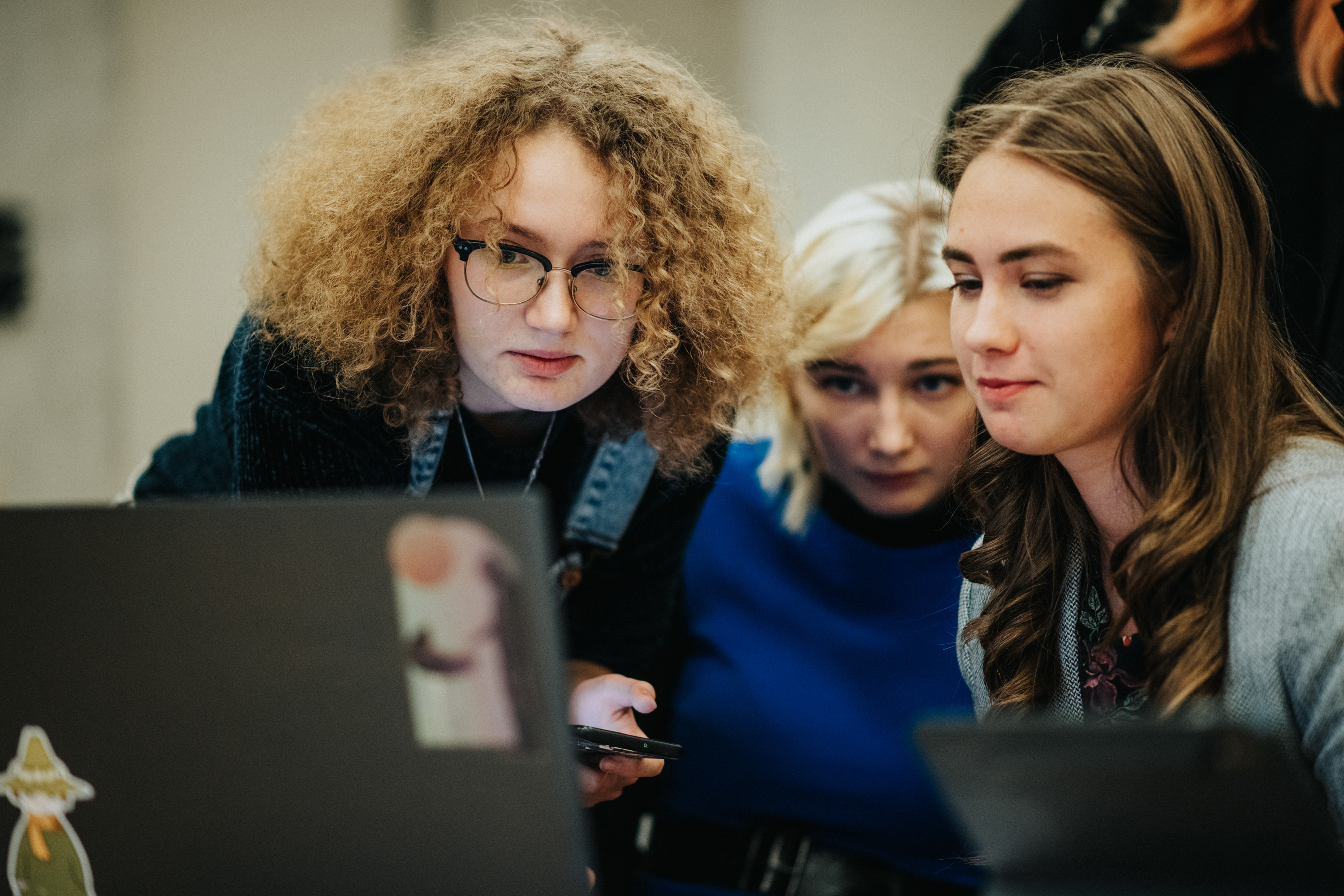 Trīs studentes skatās datorā Jauno tehnoloģiju un inovāciju dienā