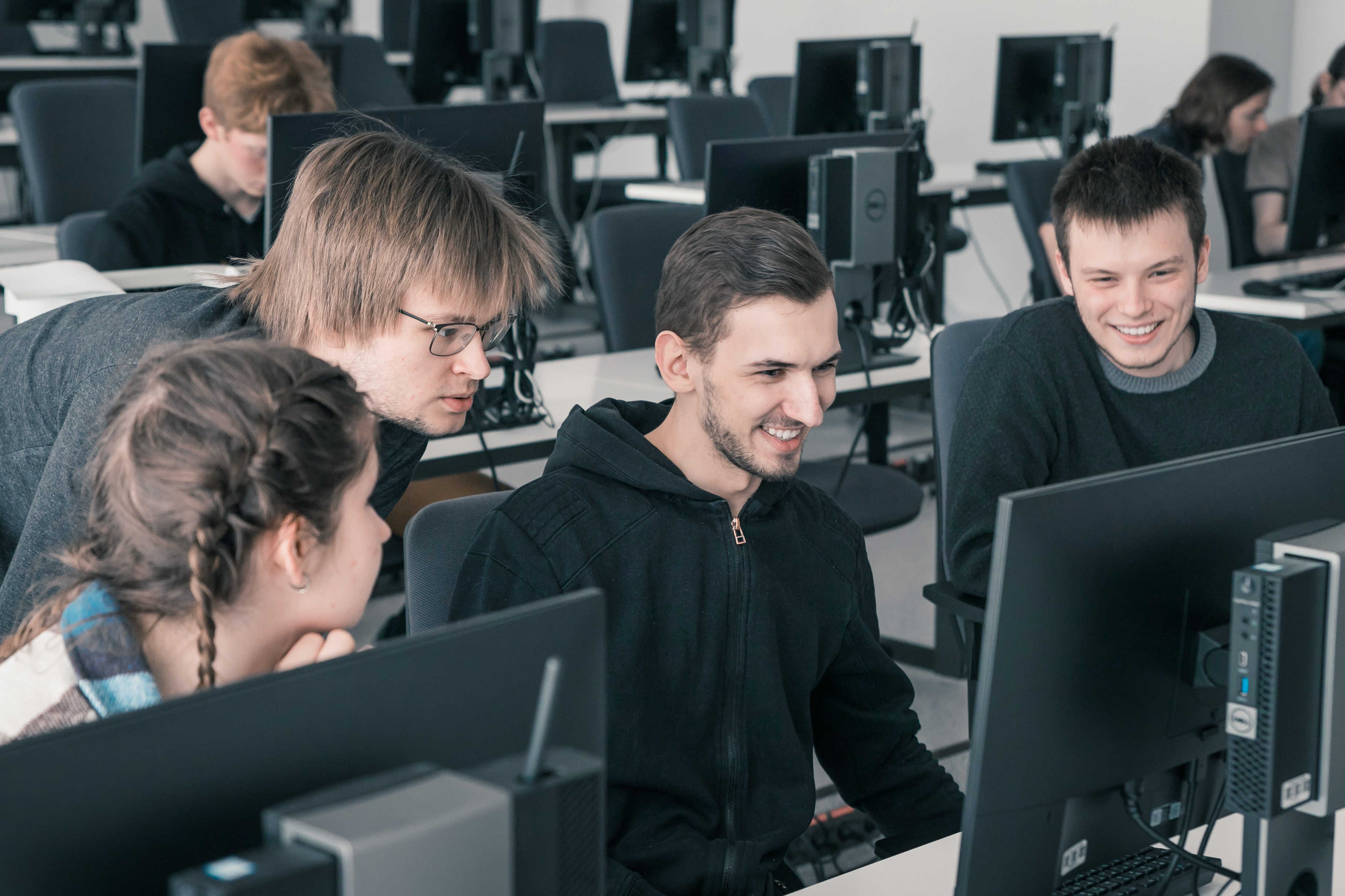 Smaidīgi studenti pie datora
