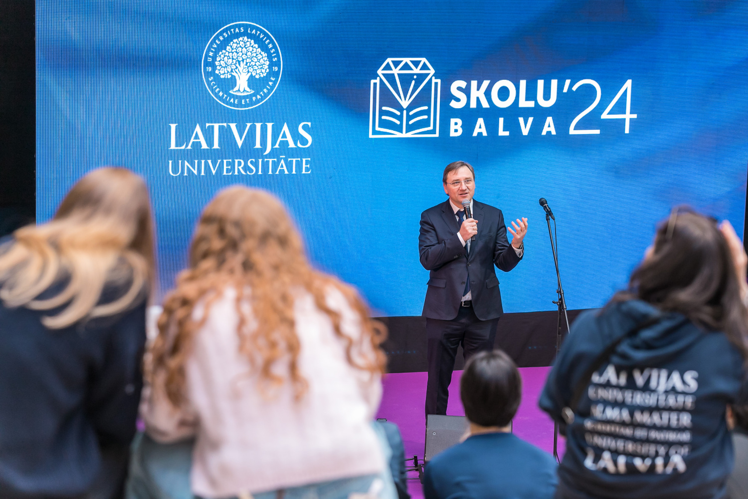 Attēla LU rektors un pasākuma "Skolu balvas 2024" apmeklētāji no mugurpuses