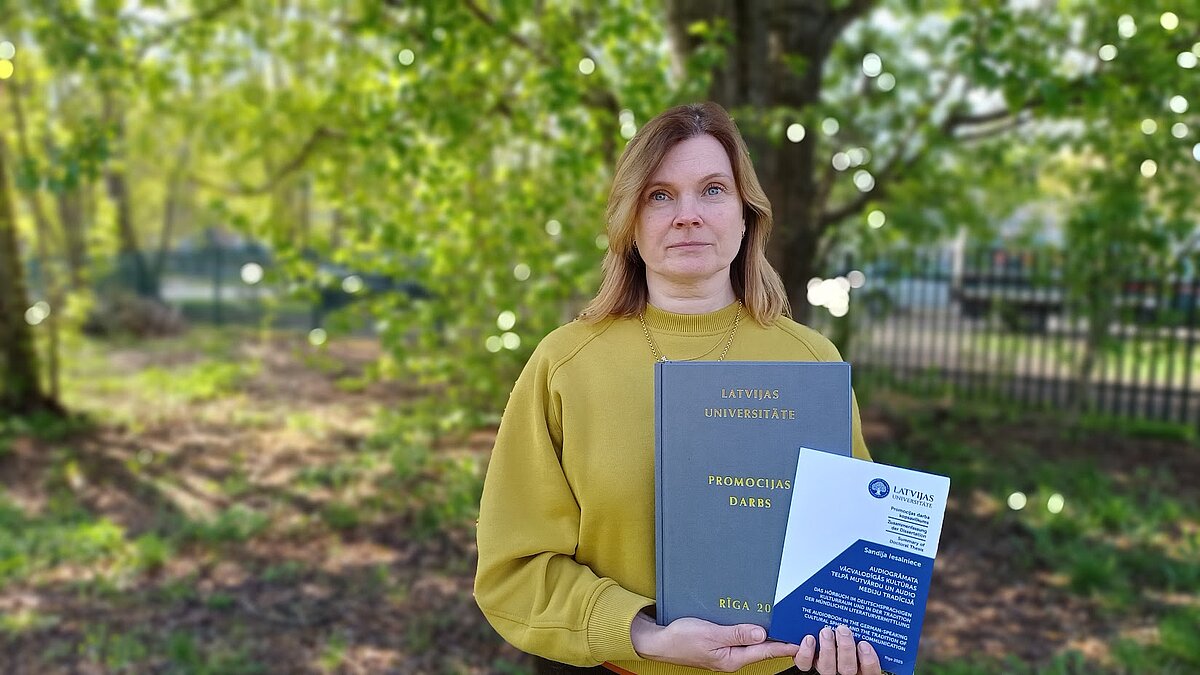 Sieviete tur rokās iesietu diplomdarbu