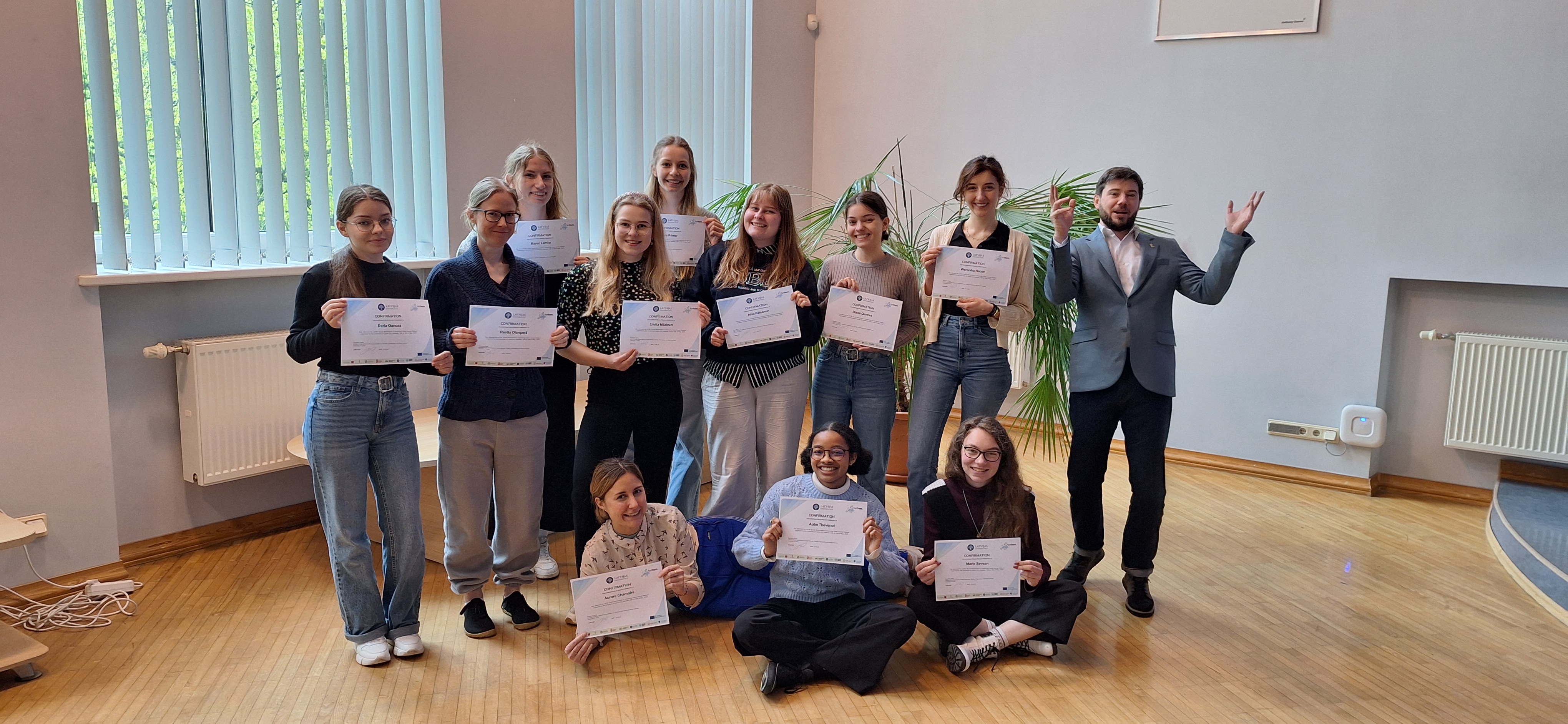 Studentu grupa priecājas par saņemtajiem diplomiem