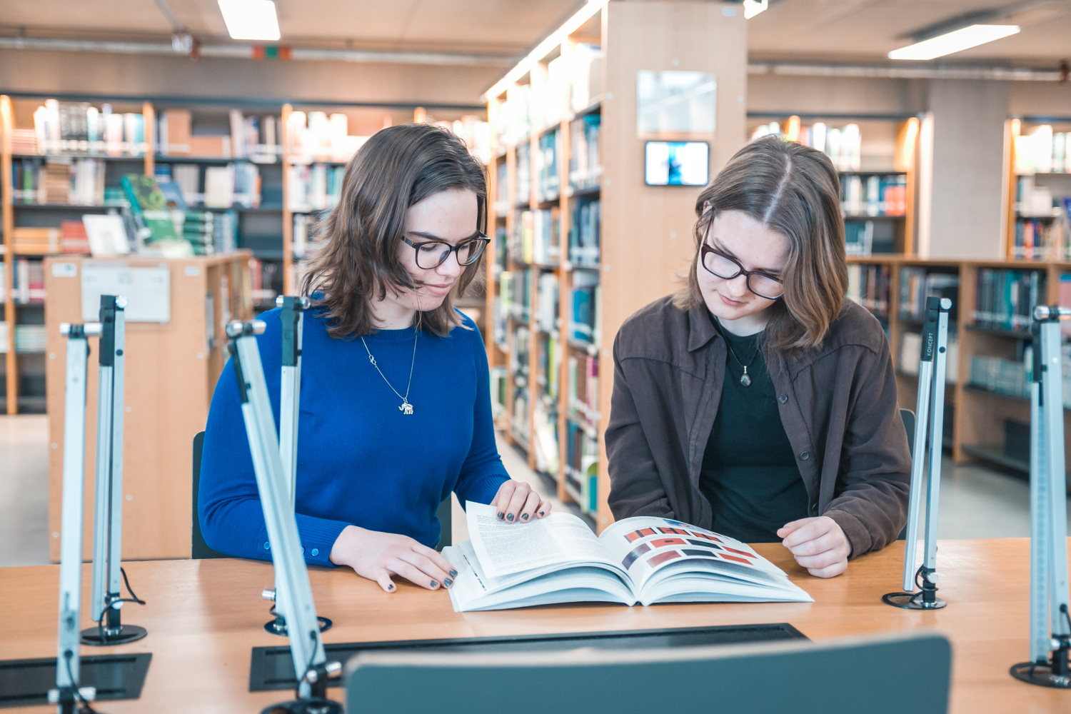 Divas studentes pēta grāmatu bibliotēkā