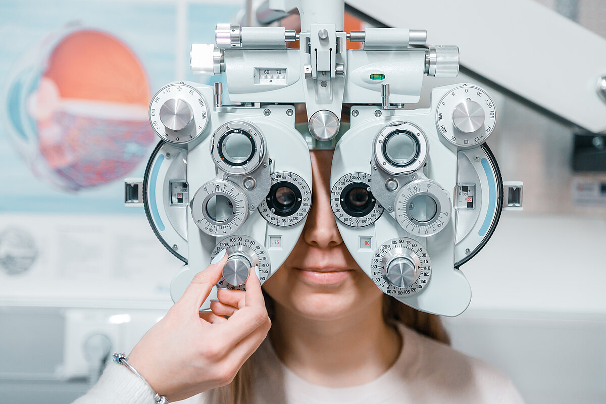 Optometrists veic redzes pārbaudi, izmantojot phoropteru pacienta acu priekšā