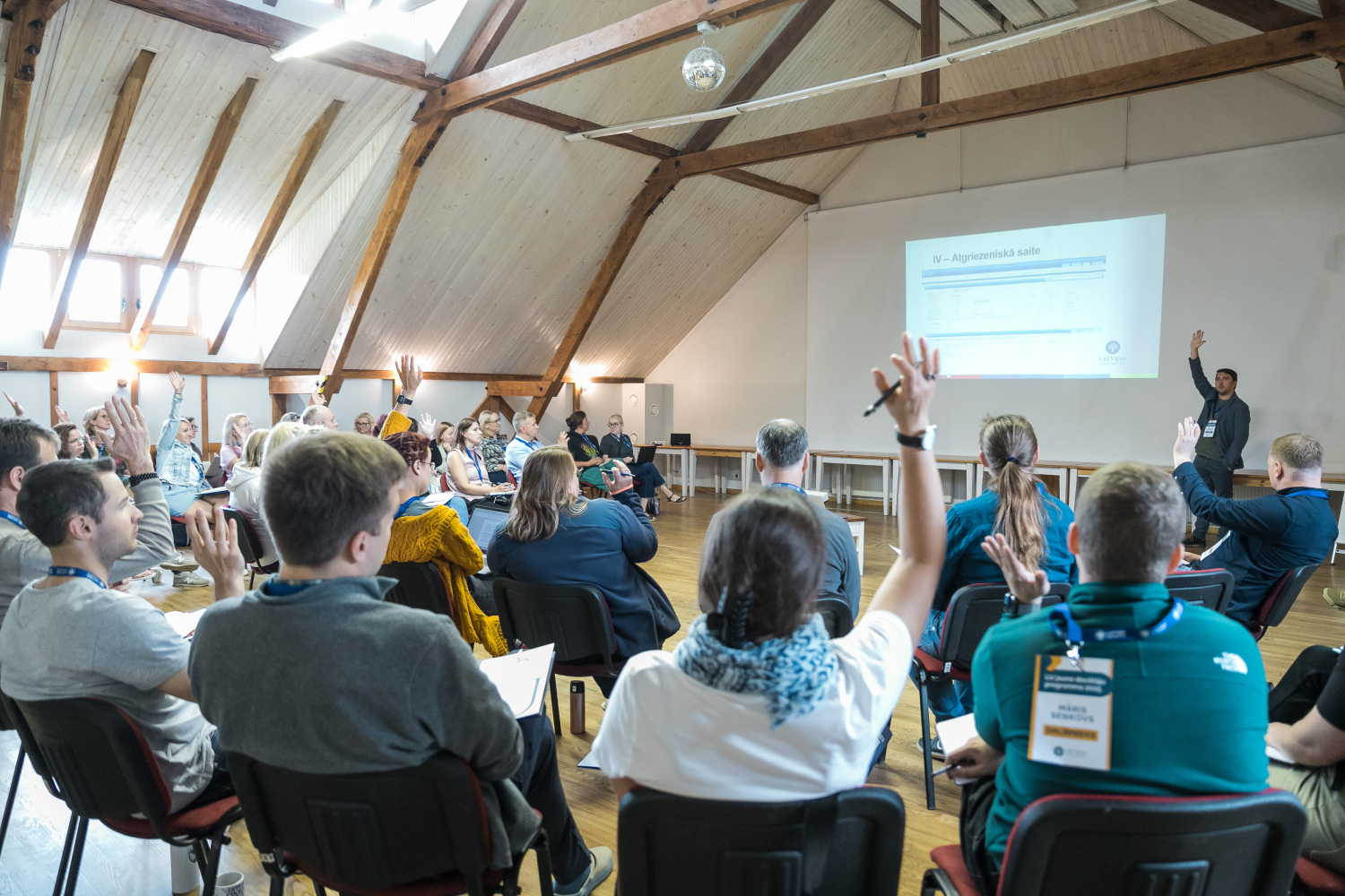 Cilvēki sēž telpā ar skatu uz prezentāciju