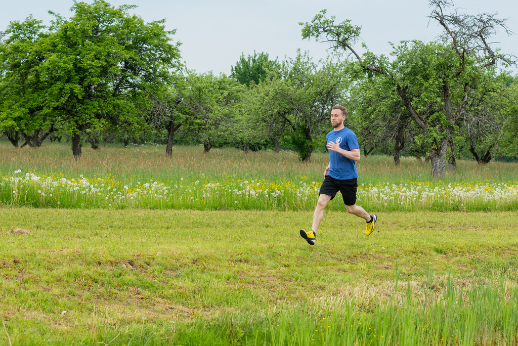 Vīrietis skrien. Fonā zaļi koki
