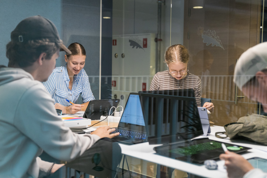 Vairāki studenti telpā pie datora