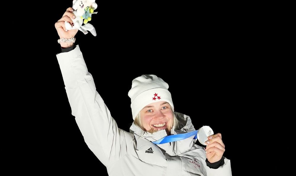 LU studente Elīna Ieva Bota tur rokās sudraba medaļu un otrā rokā mīksto mantiņu