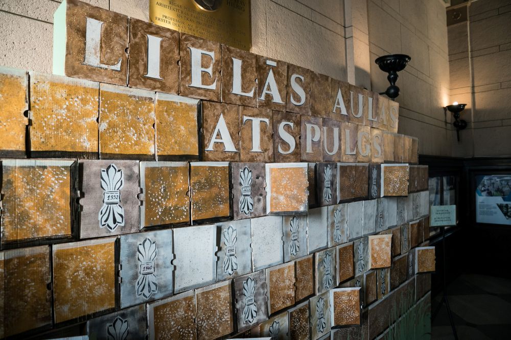  instalācija ar uzrakstu “Lielās aulas atspulgs”, veidota no dažādu krāsu un faktūru kastītēm vēsturiskā interjerā.