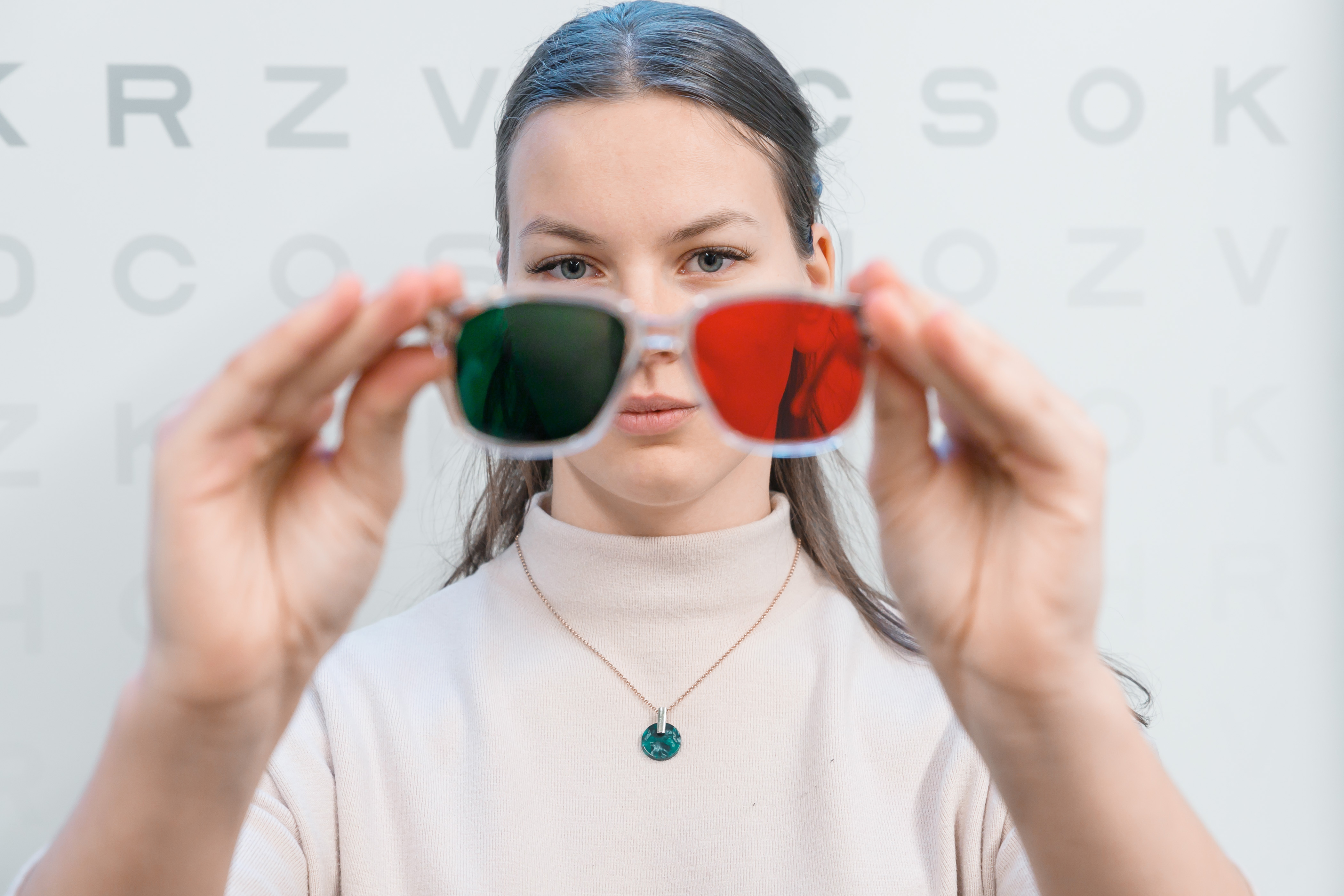 Meitene tur rokās brilles ar dažādu krāsu lēcām