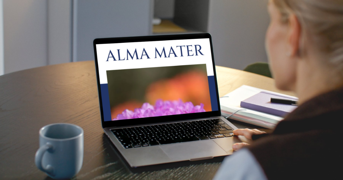 Persona sēž pie galda un skatās portatīvajā datorā lapu “Alma Mater”.