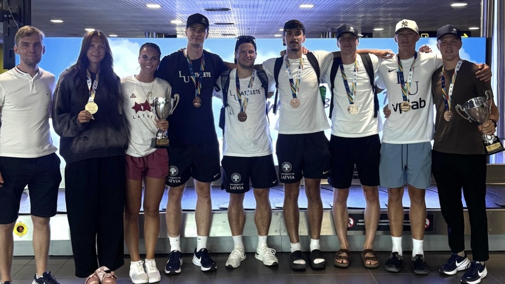 Latvijas Universitātes sporta komanda lidostā ar izcīnītajām medaļām un diviem kausiem pēc starptautiskām sacensībām.