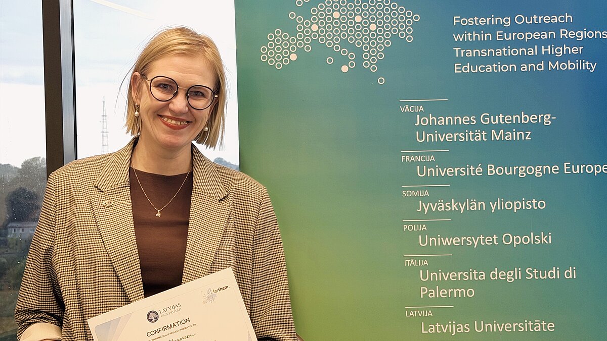 Persona stāv auditorijas priekšā un prezentē pētījumu par redzes funkcijām, kamēr klausītāji seko līdzi prezentācijai uz ekrāna.