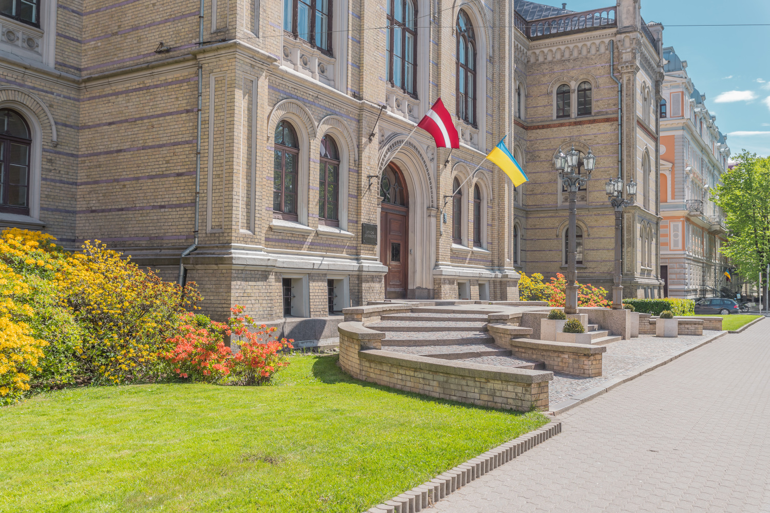 Latvijas Universitātes galvenā ēka Raiņa bulvārī 19, pie ēkas zied skaisti, krāsaino rododendru krūmi