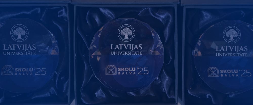 Trīs Latvijas Universitātes ‘Skolu balva ’25’ kristāla balvas, izliktas kastītēs ar tumšu auduma oderi.